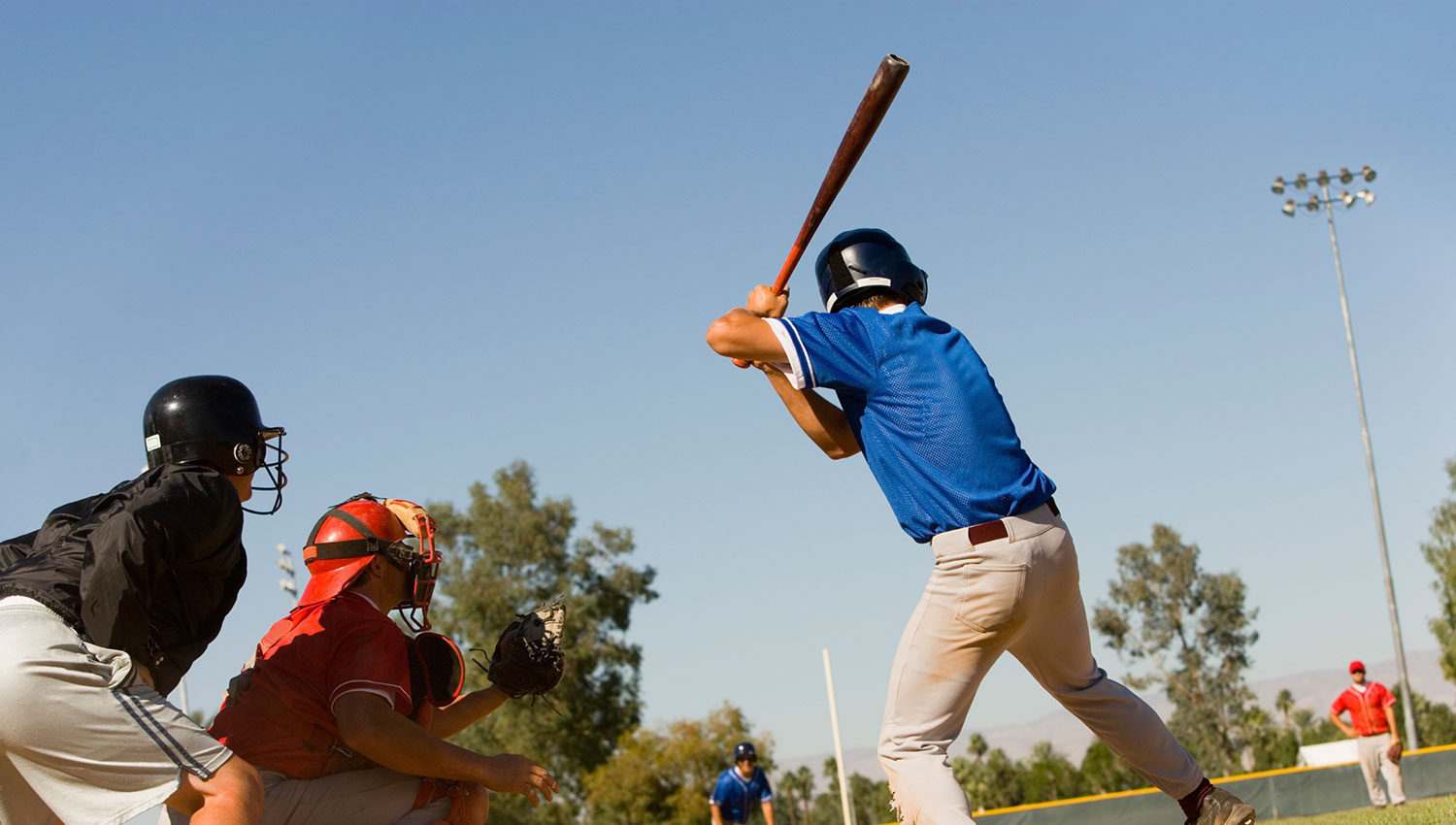 blue jersey vs red jersey playing baseball on a sunny day