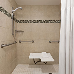 ADA accessible suites with white shower background and bath seat